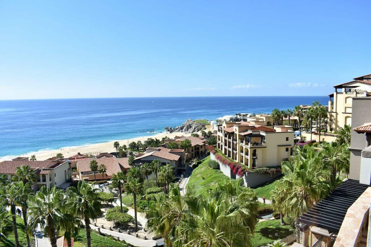 Los Cabos Travel Guide a view of a beach and palm trees from a balcony