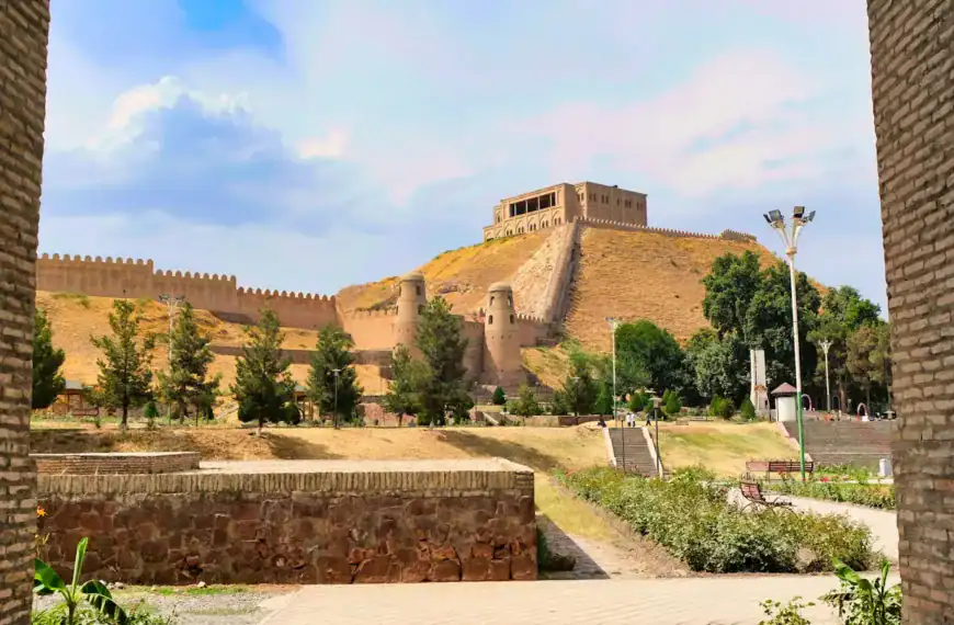 Tajikistan Travel Guide a view of a castle through two brick walls