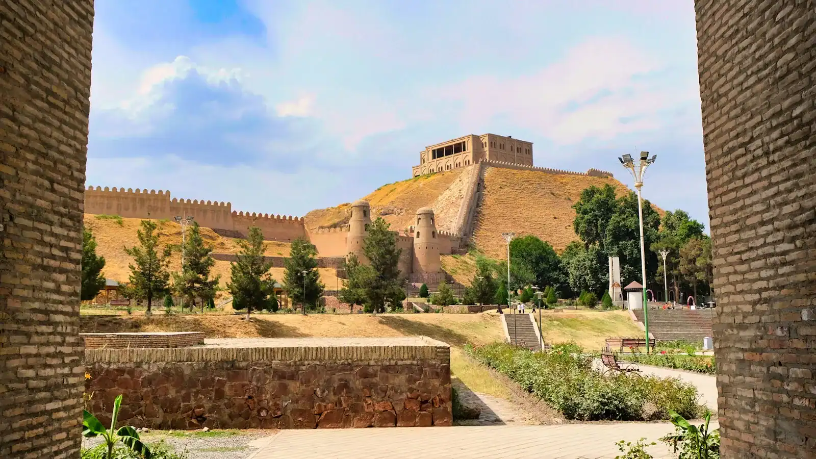 Tajikistan Travel Guide a view of a castle through two brick walls