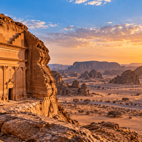 Ancient rock-cut architecture surrounded by sandstone formations and sweeping desert landscape in AlUla, Saudi Arabia.