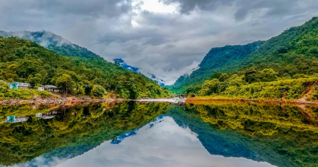 Bangladesh travel guide green mountain beside body of water under cloudy sky during daytime