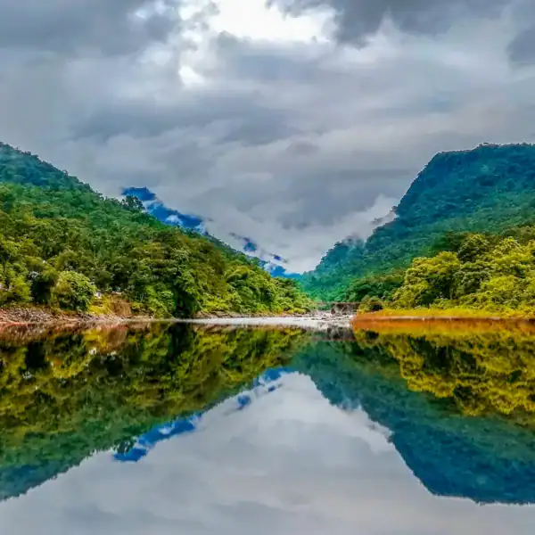 Bangladesh travel guide green mountain beside body of water under cloudy sky during daytime