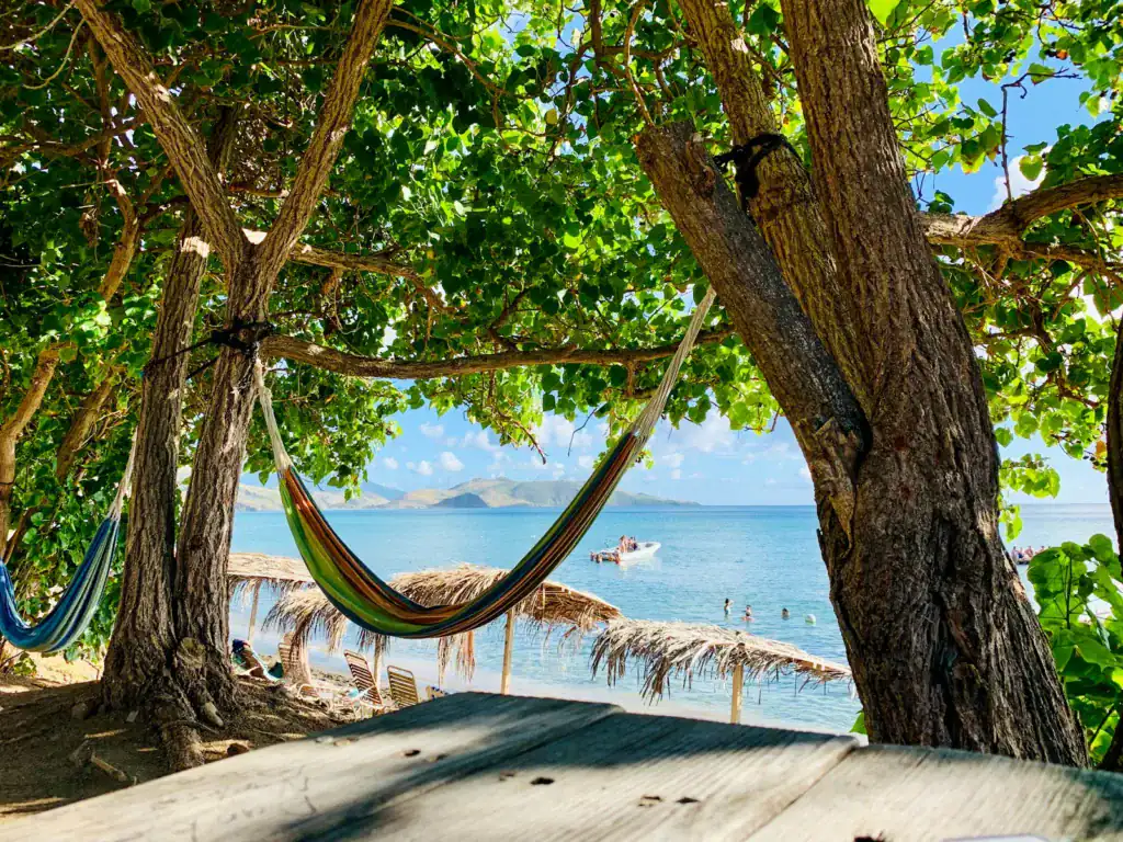 St Kitts and Nevis travel guide a hammock hanging between two trees on a beach