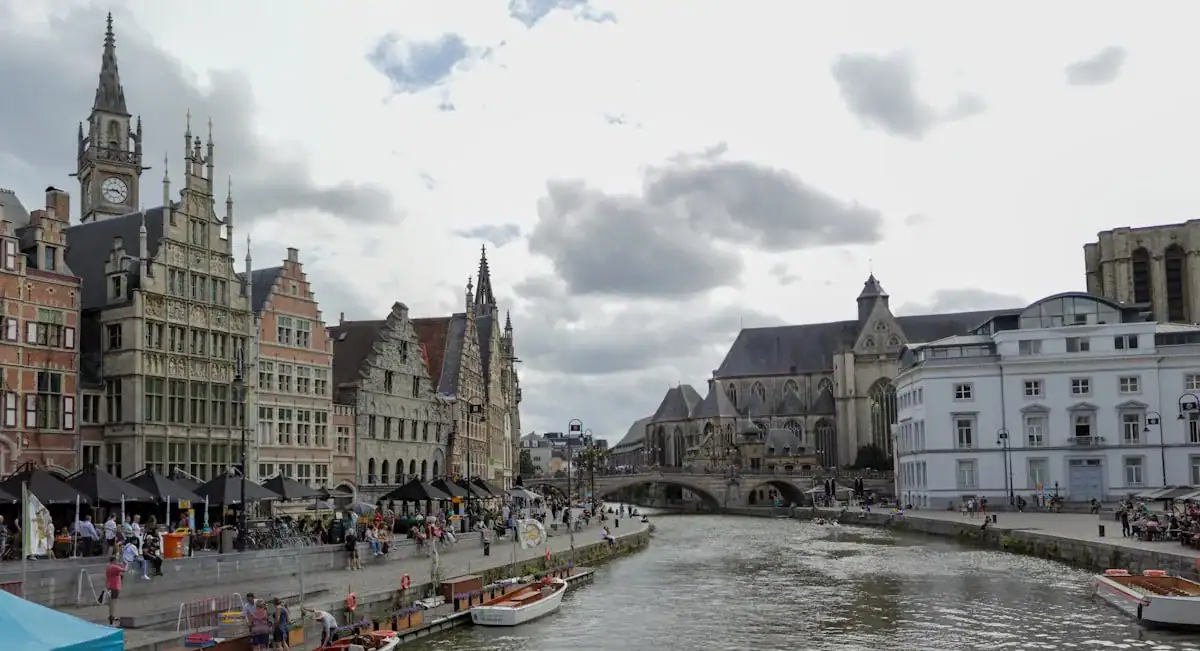 Ghent Travel Guide a river with boats and buildings along it