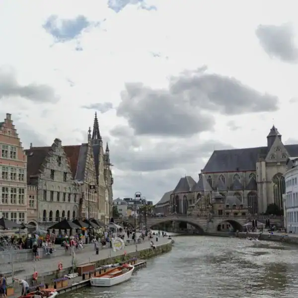 Ghent Travel Guide a river with boats and buildings along it