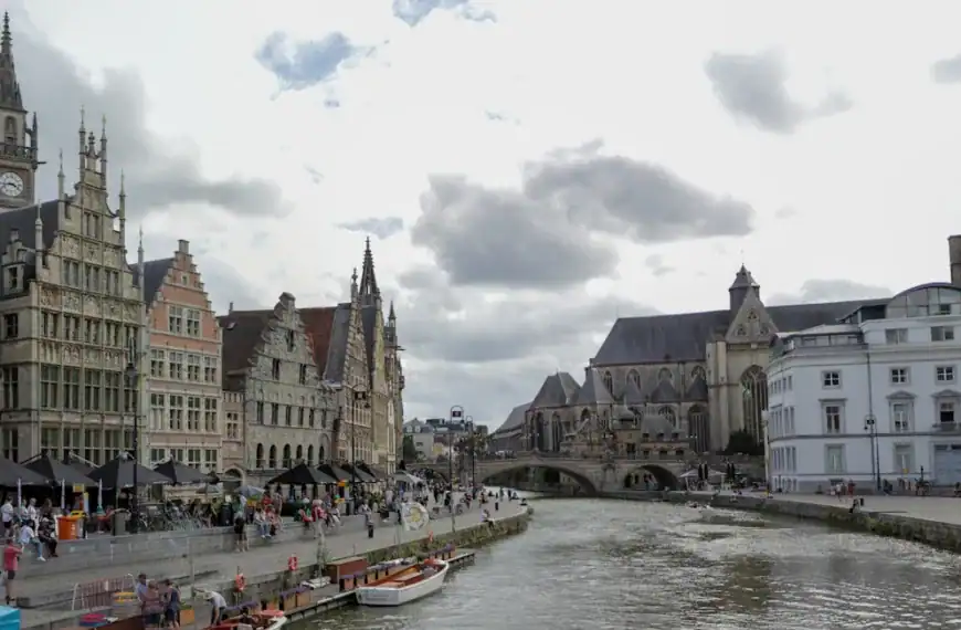 Ghent Travel Guide a river with boats and buildings along it