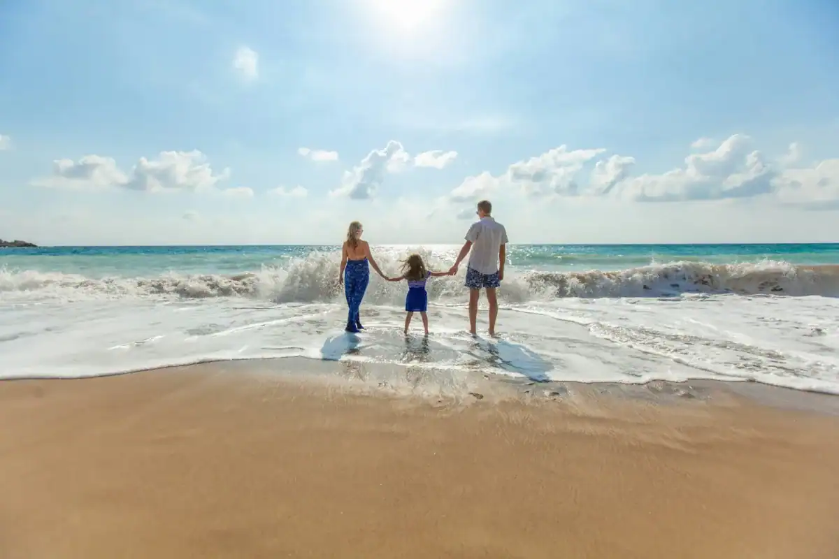 Best Time to Travel man, woman and child holding hands on seashore