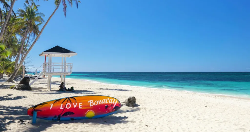 Boracay Travel Guide a colorful surfboard sitting on a beach next to a life guard tower