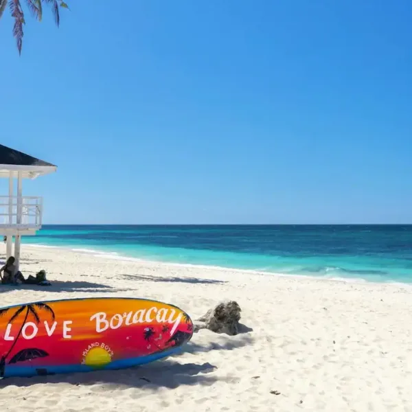 Boracay Travel Guide a colorful surfboard sitting on a beach next to a life guard tower