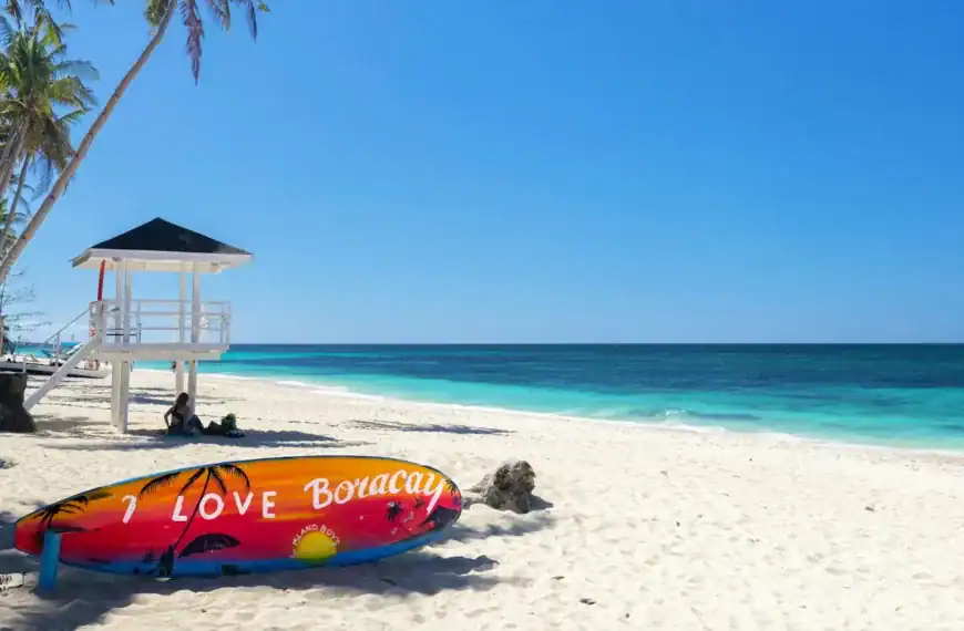 Boracay Travel Guide a colorful surfboard sitting on a beach next to a life guard tower