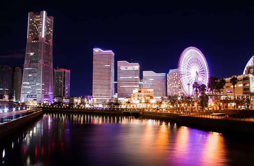 lighted city buildings near body of water at night